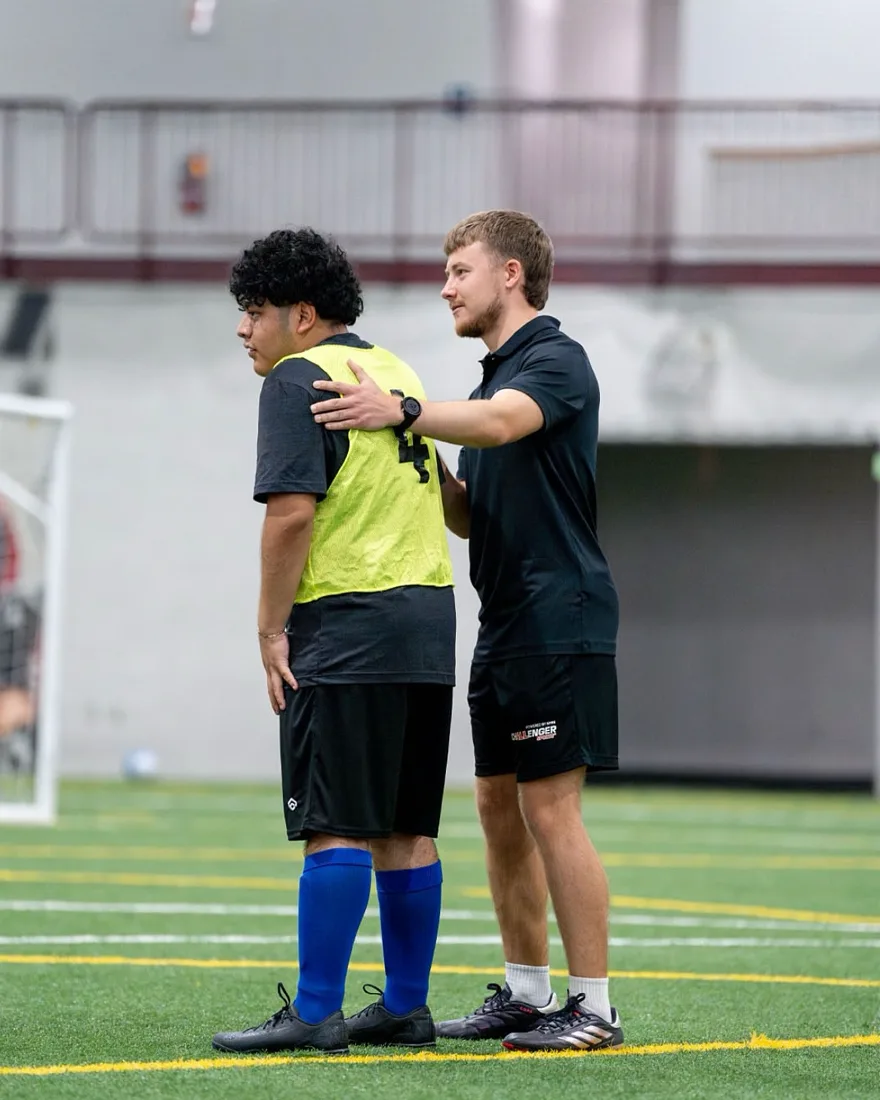 Lucas Sutherland on the pitch with a hand on a player&rsquo;s shoulder, talking him through a moment in the session.